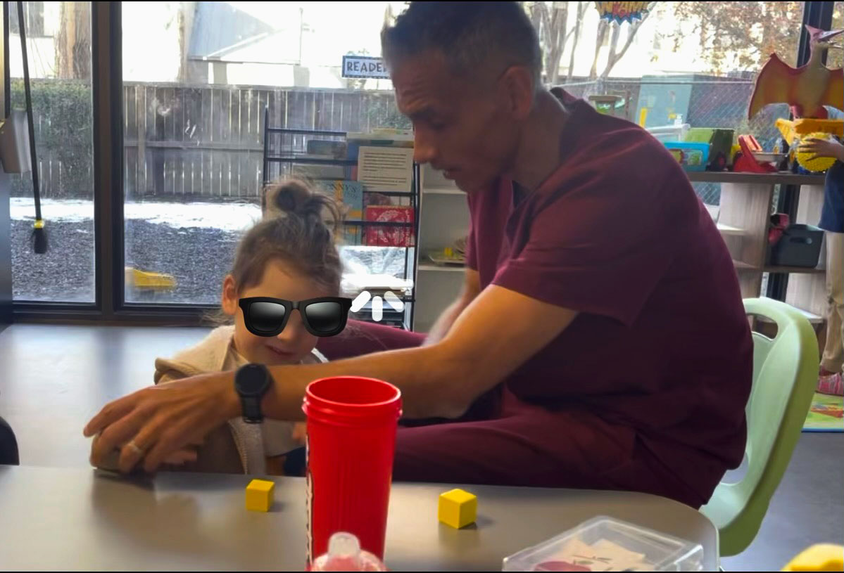 A therapist supporting a child during an in-home ABA session